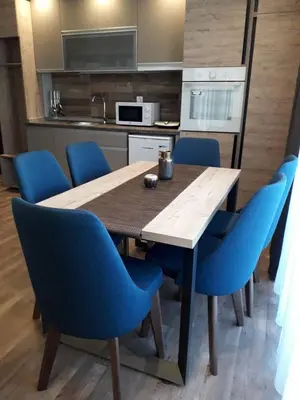 a kitchen with a wooden table and blue chairs at Apartman Lux Kopaonik in Kopaonik