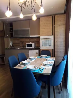 a dining room table with blue chairs in a kitchen at Apartman Lux Kopaonik in Kopaonik