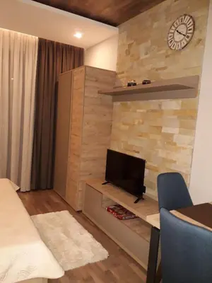 a living room with a tv and a wall with a clock at Apartman Lux Premier 09 Kopaonik in Kopaonik