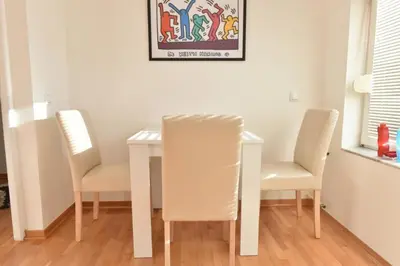 a dining room table with two chairs and a white table at Promenada apartmani in Kruševac