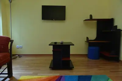 a room with a table and a tv on a wall at Promenada apartmani in Kruševac