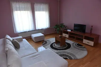 a living room with a white couch and a television at Promenada apartmani in Kruševac