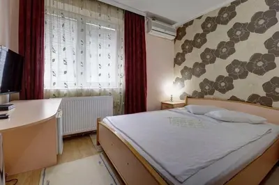 a bedroom with a bed and a desk and a window at PERLA Leskovac in Leskovac