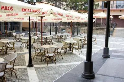 an outdoor cafe with tables and chairs and umbrellas at Hill Wellness & Spa in Jagodina