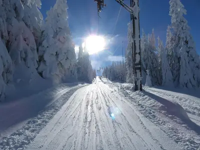 a snow covered road with the sun in the background at Sky apartments Kopaonik in Kopaonik