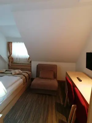 a bedroom with a bed and a chair and a desk at Kopaonik011 Konaci&WoodSide Apartments in Kopaonik