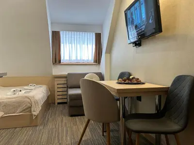 a room with a table and a bed and a television at Sweet Home Konaci in Kopaonik