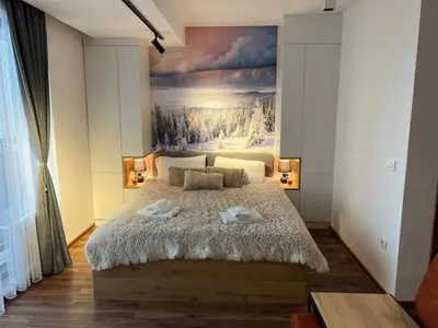 a bedroom with a large bed with a painting on the wall at Apartmani TIM & SPA CENTAR in Kopaonik