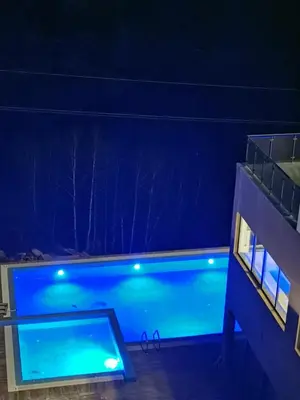 a swimming pool at night with blue illumination at Apartmani TIM & SPA CENTAR in Kopaonik
