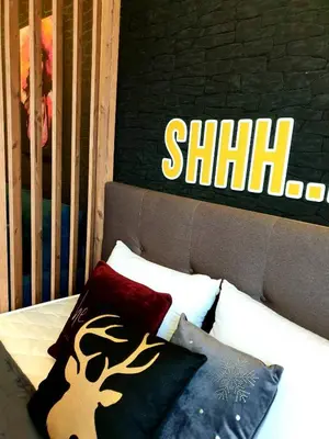 a bed with pillows and a sign on a wall at Queen of Kop Milmari in Kopaonik