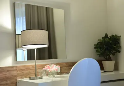 a lamp on a table in front of a mirror at Hotel Sole in Niš