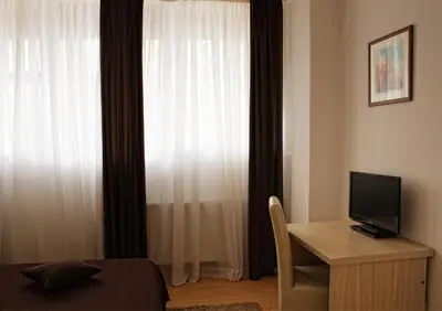 a bedroom with a bed and a desk with a television at Garni Hotel Hamburg in Zaječar