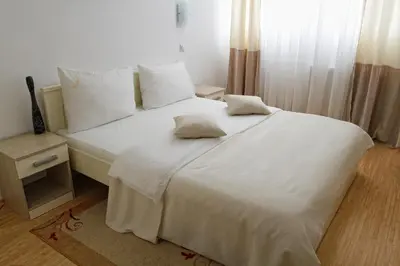 a white bed with two pillows on it in a bedroom at Garni Hotel Hamburg in Zaječar