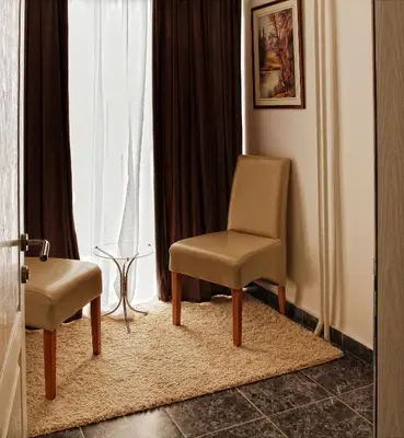a chair and a stool in front of a window at Garni Hotel Hamburg in Zaječar