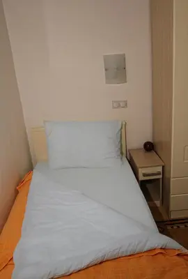 a white bed in a small room with a table at Garni Hotel Hamburg in Zaječar