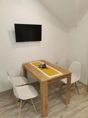 a dining room table with white chairs and a television at Vila Vrh in Crni Vrh