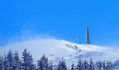a snow covered mountain with a tower on top of it at Vila Treska 98 in Kopaonik