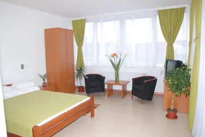 a bedroom with a bed and two chairs and a window at M Garni Hotel in Vranje