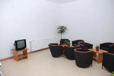 a room with chairs and tables and a tv at M Garni Hotel in Vranje