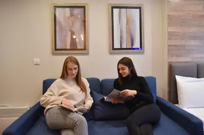 two women sitting on a couch in a room at Milmari Apartment 43 Premier Pollo in Kopaonik