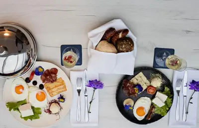 a table with two plates of food and a basket of bread at Hotel Fontana Vrnjačka Banja in Vrnjačka Banja