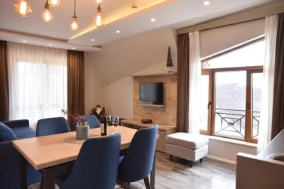 a dining room with a table and chairs and a television at Milmari Resort Premier 46 in Kopaonik