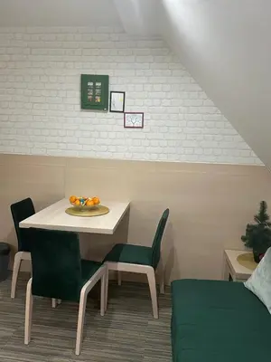 a dining room with a white table and green chairs at Apartmani Air in Kopaonik