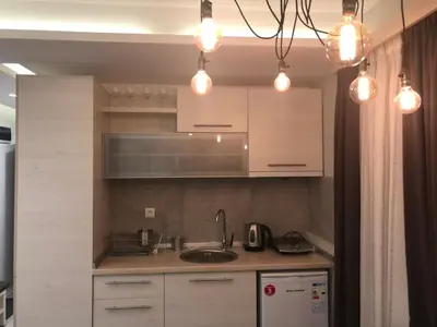 a kitchen with white cabinets and a sink and lights at Milmari Resort in Kopaonik