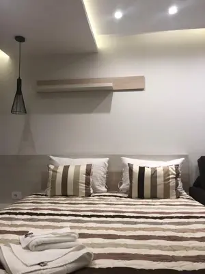 a bedroom with a bed with striped sheets and pillows at Milmari Resort in Kopaonik