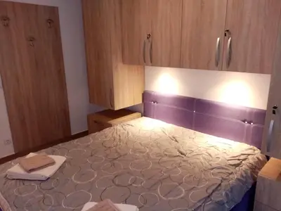 a bedroom with a large bed with wooden cabinets at Kallas lux apartman in Kopaonik