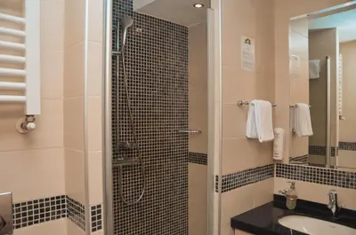 a bathroom with a shower with a sink and a mirror at Apartman Mitra Angella Konaci in Kopaonik