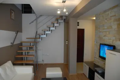 a living room with a staircase and a tv at Villa Milmari in Kopaonik