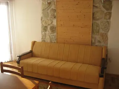 a couch in a living room with a stone wall at Villa Sofija in Kopaonik