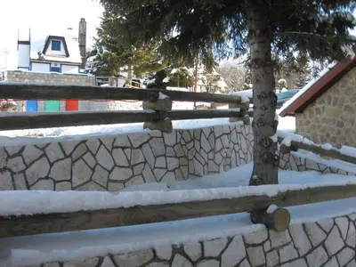 a wooden fence with a tree in the snow at Villa Sofija in Kopaonik