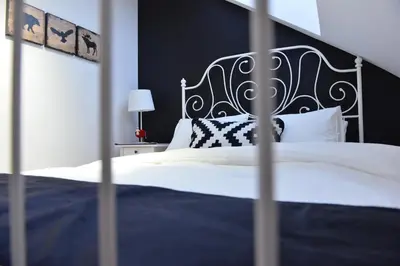 a bedroom with a white bed with a black headboard at Višnja apartment in Kopaonik