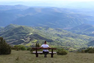 a man sitting on a bench overlooking a valley at Hotel Kraljevi Čardaci in Kopaonik