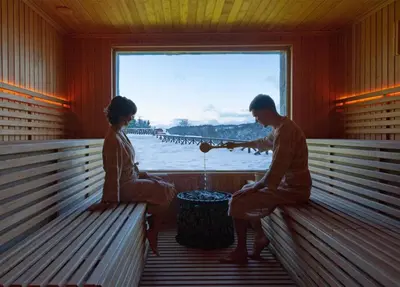 a man and a woman sitting on benches in a room at Hotel Kraljevi Čardaci in Kopaonik