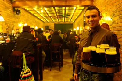 a man holding a tray of beer in a restaurant at Hotel Kraljevi Čardaci in Kopaonik