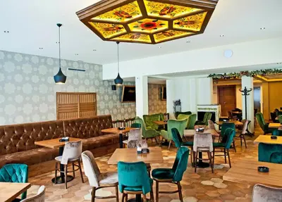 a restaurant with wooden tables and green chairs at Hotel Kraljevi Čardaci in Kopaonik
