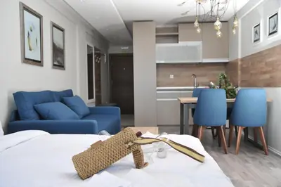 a room with a bed and a kitchen with blue chairs at Milmari Resort, Apartman Premier 27 in Kopaonik