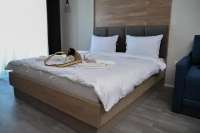 a bedroom with a large bed with white sheets and shoes at Milmari Resort, Apartman Premier 27 in Kopaonik