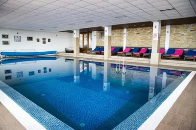 a large swimming pool with blue water in a building at Milmari Resort, Apartman Premier 27 in Kopaonik