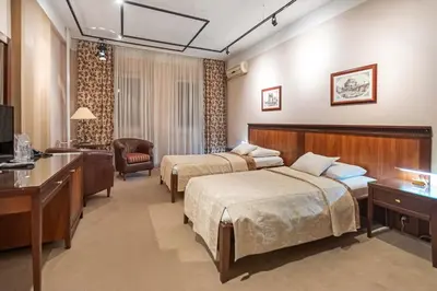 a hotel room with two beds and a desk at The Regent Club Hotel in Niš