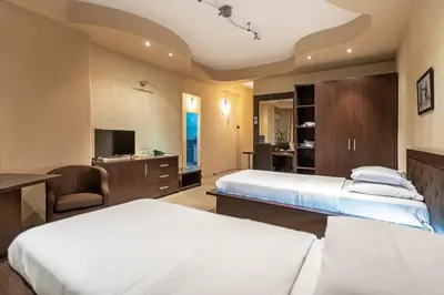 a hotel room with two beds and a desk at The Regent Club Hotel in Niš