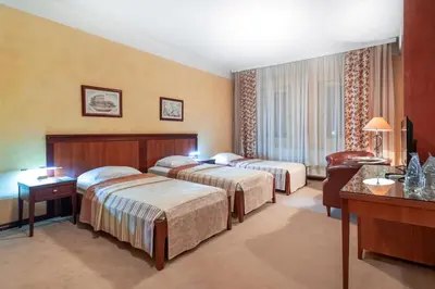a hotel room with two beds and a desk at The Regent Club Hotel in Niš