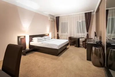 a bedroom with a bed and a table and chairs at The Regent Club Hotel in Niš