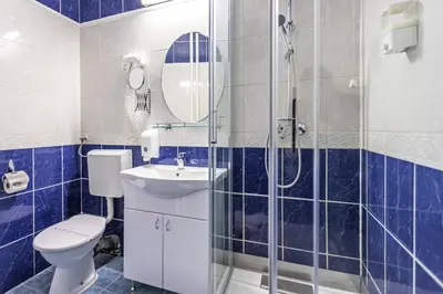 a blue tiled bathroom with a toilet and a shower at The Regent Club Hotel in Niš