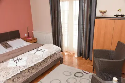 a bedroom with a bed and a chair and a window at Blue House Apartment in Niš