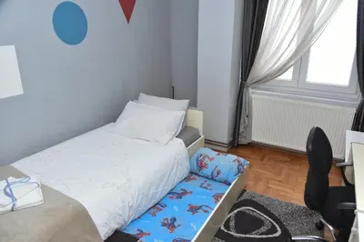a small bedroom with a bed and a chair at Blue House Apartment in Niš