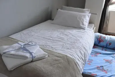 a bed with white sheets and a towel on it at Blue House Apartment in Niš